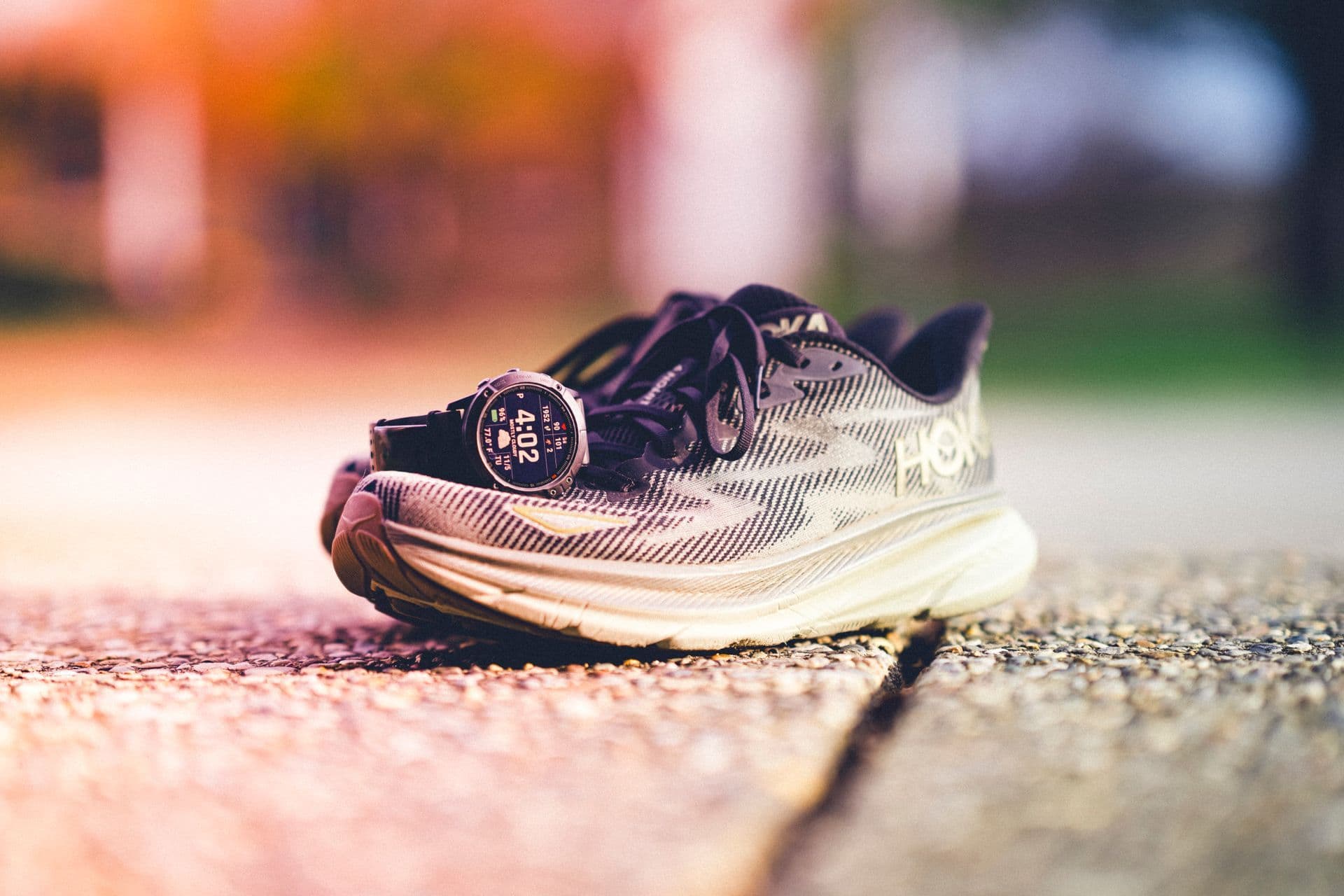 Running shoes and a sports watch on a sunny path